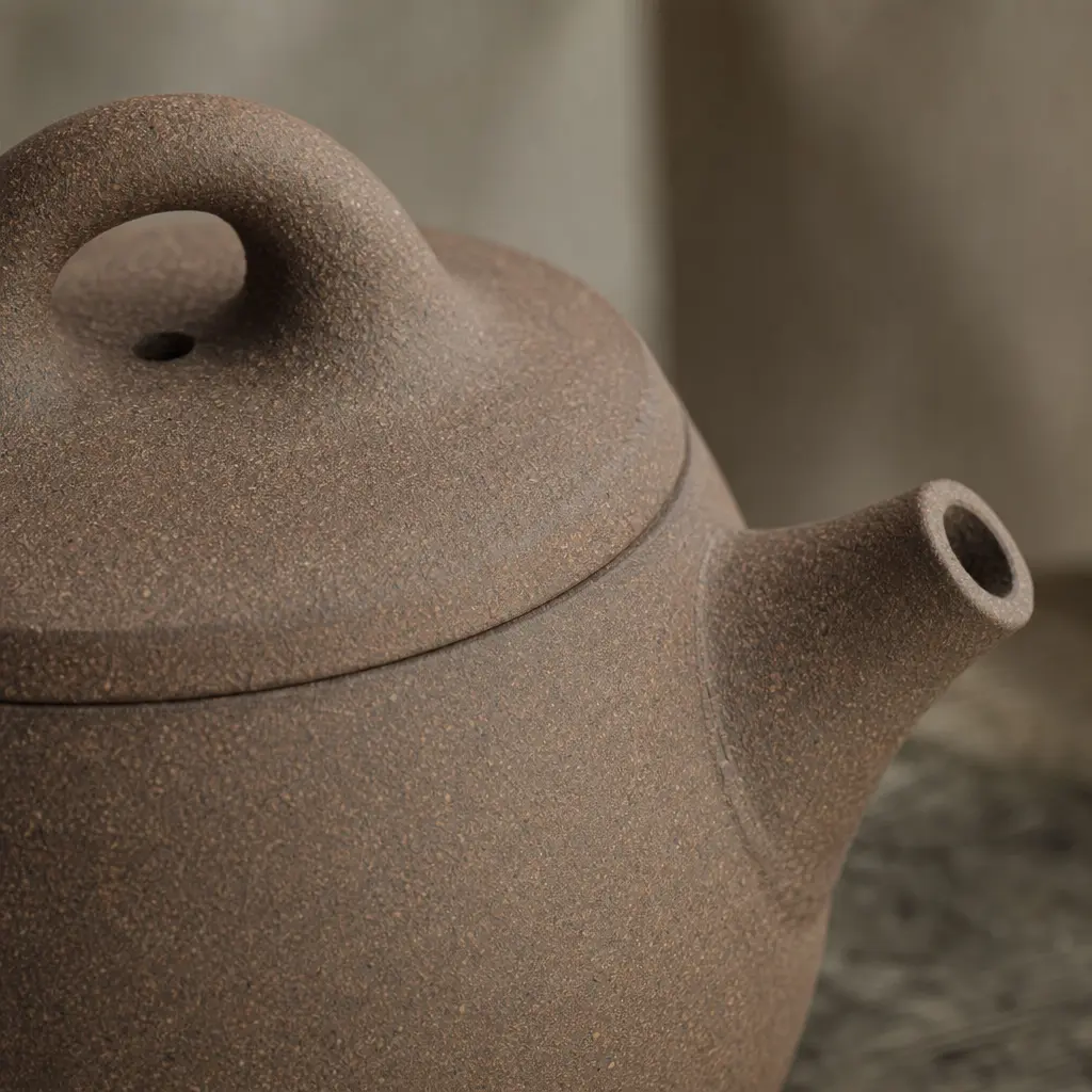 Aged zisha clay teapot surface revealing warm ochre and muted purple-brown ceramic grain texture in soft diffused light